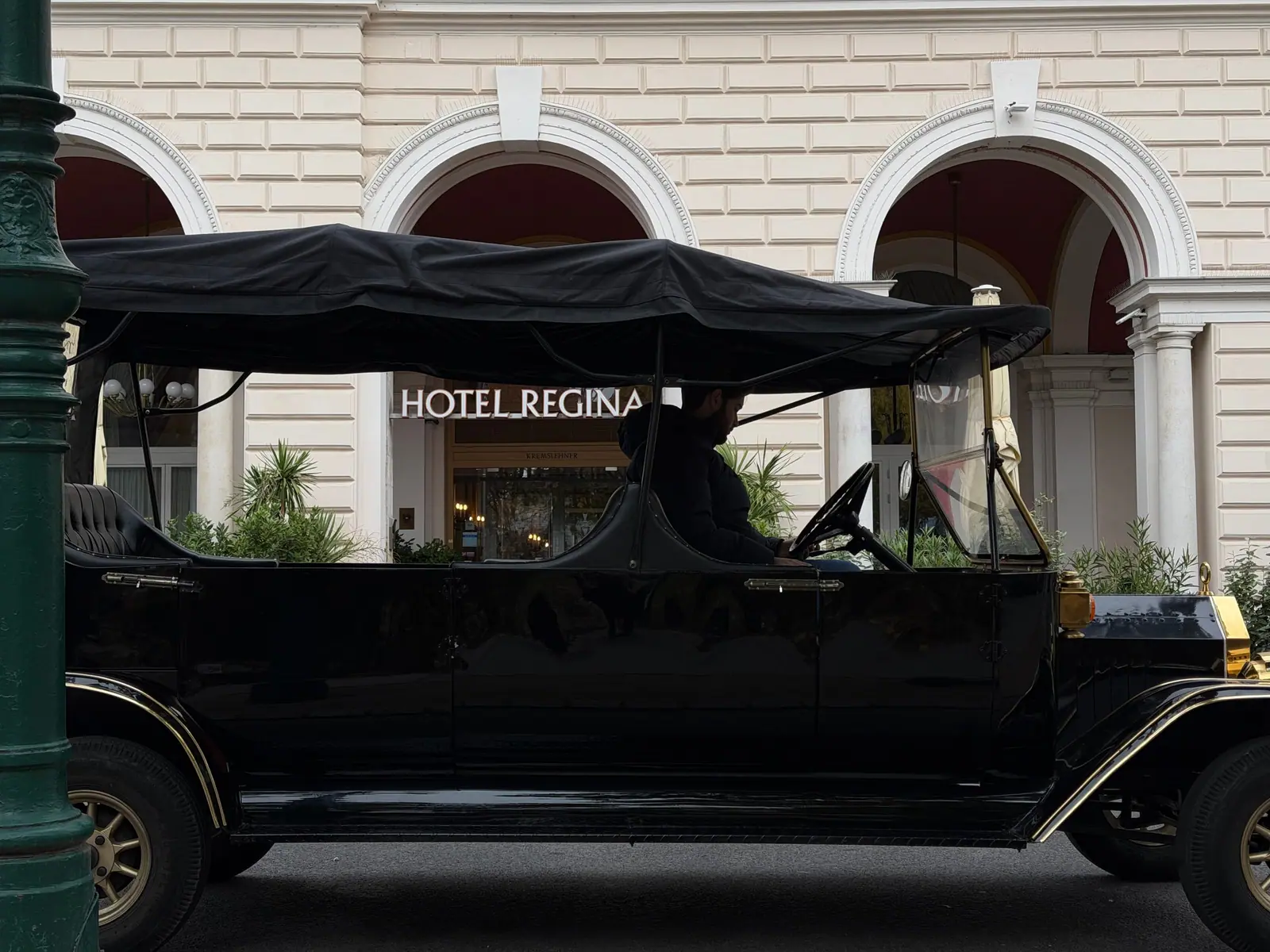 The long seven-seat vintage car under the arches of Hotel Regina